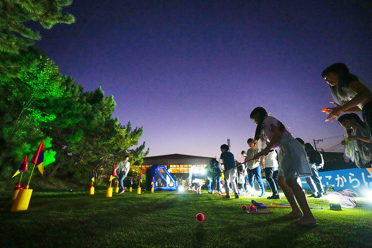 光りで彩るゴルフ場であそぼう：ライトアップされた夜のゴルフ場で遊ぶ人々